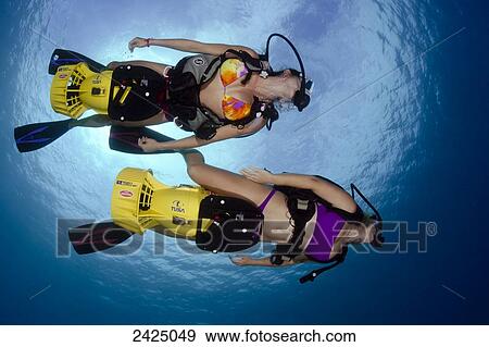 Stock Photo - Hawaii, Two young women on underwater scooters.. Fotosearch