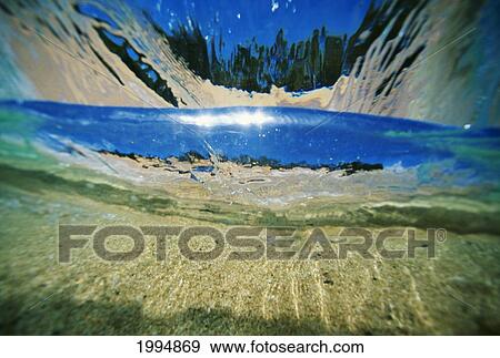 Stock Photo - Hawaii, Underwater Breaking Wave, Sand, Sky And Trees Visible Through Clear Water. Fotosearch
