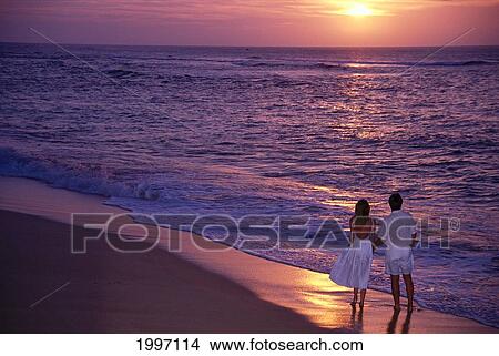 Picture - Hawaii, View From Behind Couple Walking Along Beach Shoreline At Sunset A06A. Fotosearch