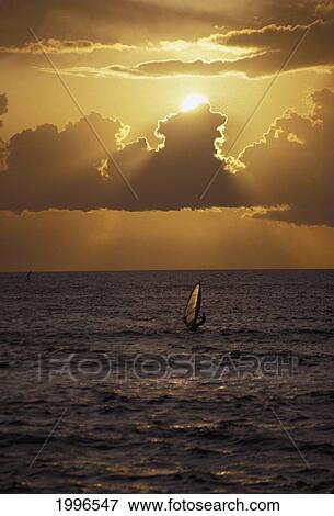 Stock Photo - Hawaii, Windsurfer In Action During Dramatic Amber Sunset, Silhouette. Fotosearch