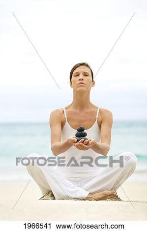 Stock Image - Hawaii, Woman Holding Stack Of Stones In Hands, Ocean In Background.. Fotosearch