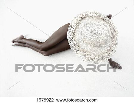 Stock Image - Hawaii, Woman Lays On The Sand With Straw Wide Brim Hat.. Fotosearch