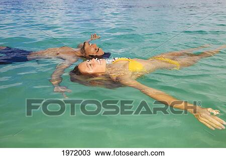 Hawaii, Young Couple Floating In Tropical Ocean Water. View Large Photo Image Stock Image - Hawaii, Young Couple Floating In Tropical Ocean Water.. Fotosearch