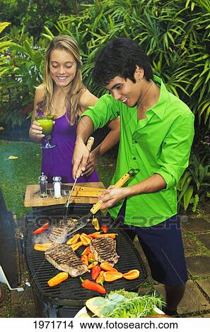 Picture - Hawaii, Young Couple Having Outdoor Barbecue In Tropical Garden.. Fotosearch
