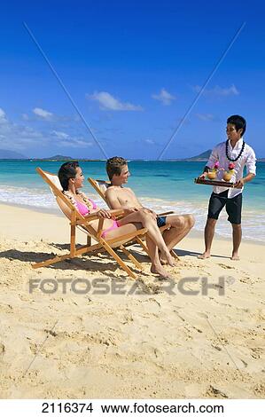 Hawaii, Young couple on the beach in lounge chairs with tropical drinks. View Large Photo Image Picture - Hawaii, Young couple on the beach in lounge chairs with tropical drinks.. Fotosearch