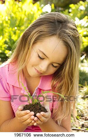 Stock Photograph - Hawaii, Young Girl Holding Fern Seedling In Mound Of Dirt.. Fotosearch