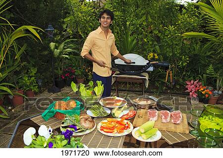 Stock Image - Hawaii, Young Man Preparing Outdoor Barbecue Feast In Hawaii Garden.. Fotosearch