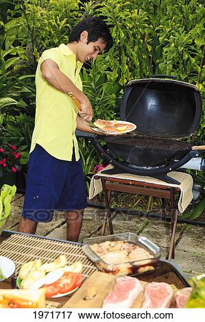 Stock Photo - Hawaii, Young Man Preparing Outdoor Barbecue Feast In Hawaii Garden.. Fotosearch
