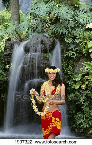 Stock Image - Hawaiian Girl Holding Lei In Front Of Waterfall, Wearing Pareo, Smiling A38A. Fotosearch