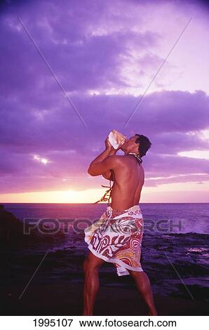 Stock Photo - Hawaiian Man Blows Conch Shell At Beach, Sunrise With Purple And Yellow Sky.. Fotosearch