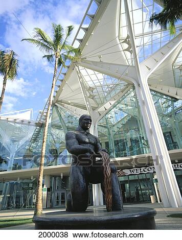 Stock Photo - Hawaiian Statue In Front New Oahu Convention Center, Glass Panels And Palm Trees. Fotosearch