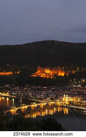 Stock Photo - Heidelberg Castle and the old bridge over River Neckar illuminated at nighttime; Heidelberg, Germany. Fotosearch