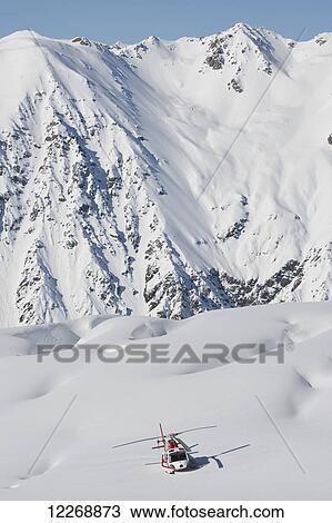 Stock Image - Helicopter landing on snowy mountain ridge; New Zealand. Fotosearch