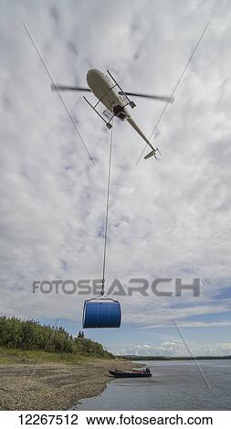 Helicopter shuttling fuel barrels to a roadless community; Old Crow, Yukon, Canada View Large Photo Image Stock Image - Helicopter shuttling fuel barrels to a roadless community; Old Crow, Yukon, Canada. Fotosearch