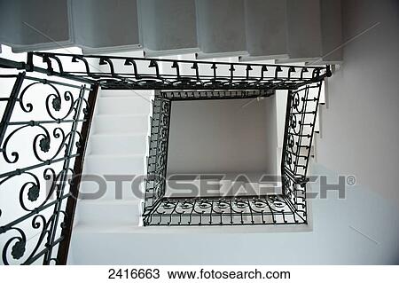 Stock Image - High angle view of a staircase with an ornate black railing; Milan, Italy. Fotosearch