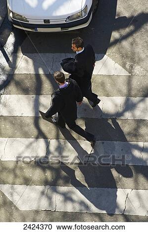 Stock Image - High angle view of businessmen crossing a street at a pedestrian crossing; Paris, France. Fotosearch
