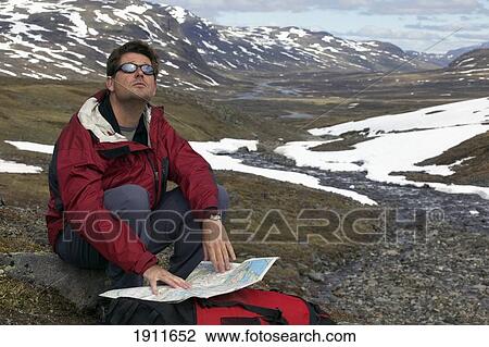 Stock Image - Hiker Checking Map Sitting On Ground, Kungsledden Trail, Sweden. Fotosearch