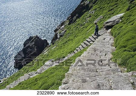Stock Image - Hiker on footpath climbing up Skellig Michael; Skellig Islands, County Kerry, Ireland, UK. Fotosearch