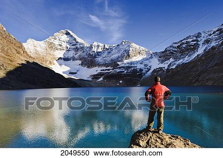 Stock Image - Hiker Overlooking Lake Mcarthur And Mount Biddle At Sunset, Yoho National Park, British Columbia. Fotosearch