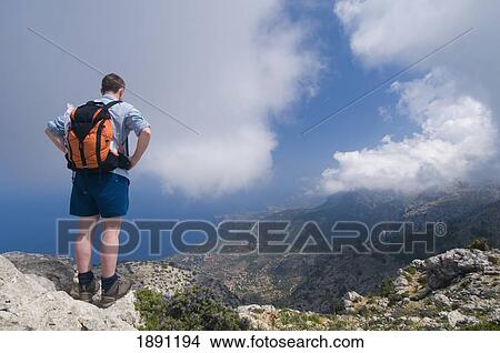 Hiker Standing On Edge Of Mountain Looking At View, Rear View View Large Photo Image Picture - Hiker Standing On Edge Of Mountain Looking At View, Rear View. Fotosearch