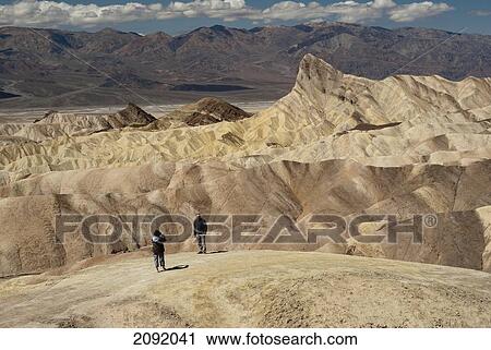 Stock Image - Hiker Taking A Photo In The Badlands Of Zabriskie Point In Death Valley National Park; California Usa. Fotosearch