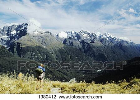 Stock Image - Hiker viewing mountains from Routeburn Track in Fiordlands National Park; New Zealand. Fotosearch