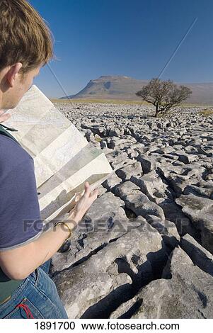 Stock Image - Hiker With Map On Limestone Pavement. Fotosearch