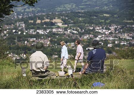 Stock Photography - Hikers having a picnic lunch rest and others walking on the famous National Trail 100 mile Cotswold Way trail above Cheltenham; Gloucestershire, England. Fotosearch
