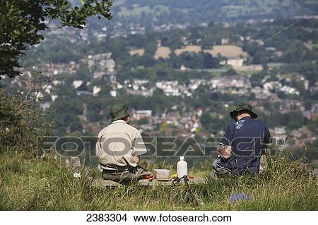 Picture - Hikers having a picnic lunch rest on the famous National Trail 100 mile Cotswold Way trail above Cheltenham; Gloucestershire, England. Fotosearch