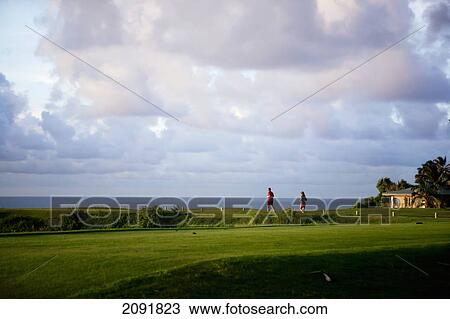 Stock Image - Hikers On The Coastal Makai Golf Course; Princeville, Kauai, Hawaii. Fotosearch