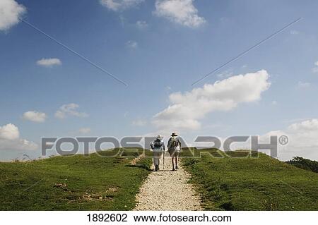 Stock Image - Hikers Walking Up Cam Long Down Hill. Fotosearch