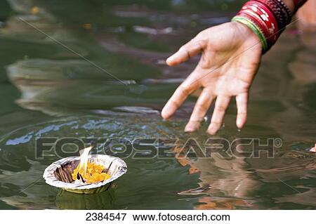 Hindu woman immersed in the holy Ganges water, casting off a container with a flame as a religious offering; Uttar Pradesh State, India View Large Photo Image Stock Photo - Hindu woman immersed in the holy Ganges water, casting off a container with a flame as a religious offering; Uttar Pradesh State, India. Fotosearch