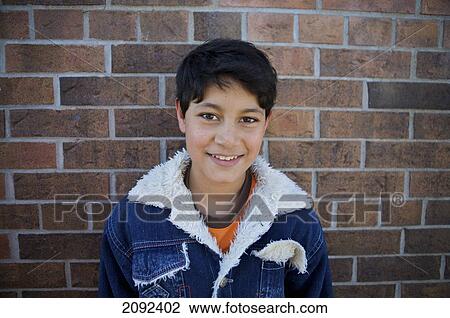 Stock Image - Hispanic Boy Against Brick Wall Of An Esl School; Guelph Ontario Canada. Fotosearch