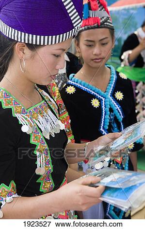 Stock Photo - Hmong Girls In Traditional Costume Looking At Photos Of Themselves At The New Year Festival, Phonsavan, Laos. Fotosearch