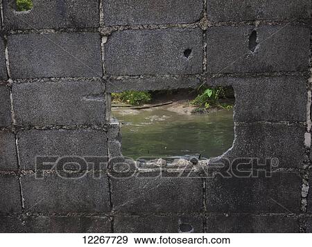 Stock Photo - Hole in a concrete block wall with water behind; Bangkok, Thailand. Fotosearch
