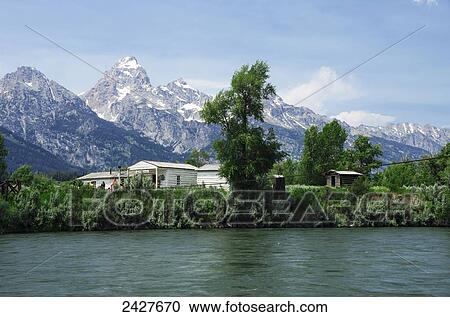 Stock Image - Holiday Menor's Homestead general store with Teton Mountains behind, across Snake River; Wyoming, United States of America. Fotosearch