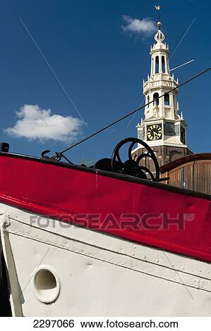 Stock Photograph - Holland, Bow of traditional Dutch barge with gabled houses in background; Amsterdam. Fotosearch