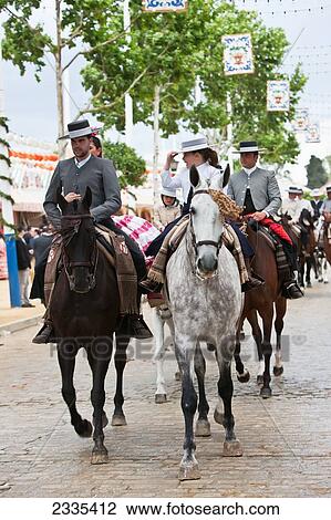 Stock Image - Horse Riding In Traditional Seville Clothing At April Fearia Festival; Seville, Andalucia, Spain, Europe. Fotosearch