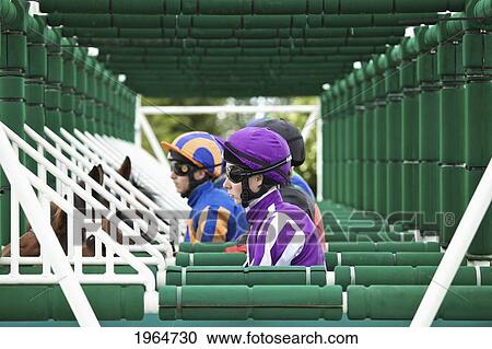 Stock Image - Horseback Riders Wait In The Starting Gates; Naas County Kildare Ireland. Fotosearch