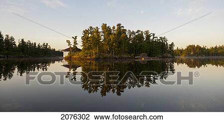 Stock Image - House And Trees Along The Water's Edge; Lake Of The Woods Ontario Canada. Fotosearch