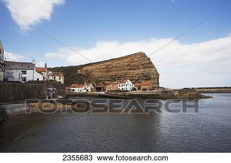 Houses Along The Water's Edge And A Rock Cliff; Staithes, Yorkshire, England View Large Photo Image Stock Image - Houses Along The Water's Edge And A Rock Cliff; Staithes, Yorkshire, England. Fotosearch