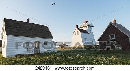 Stock Image - Houses and a lighthouse on the Atlantic coast; North Rustico, Prince Edward Island, Canada. Fotosearch