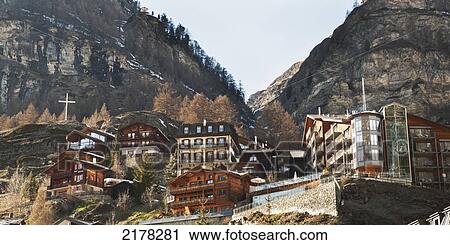 Stock Image - Housing Built On The Slope Of A Hill With A White Cross On A Rock; Zermatt Valais Switzerland. Fotosearch