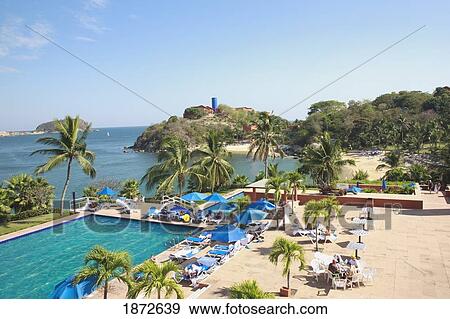 Stock Photo - Huatluco, Mexico; The Beach And Outdoor Swimming Pool Along The Ocean At Las Brisas Resort. Fotosearch