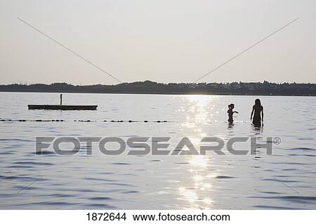 Huatluco, Mexico; Two People In The Water At A Floating Dock With The Sunlight Reflecting Off The Water View Large Photo Image Picture - Huatluco, Mexico; Two People In The Water At A Floating Dock With The Sunlight Reflecting Off The Water. Fotosearch