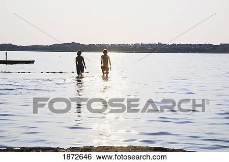 Stock Photograph - Huatluco, Mexico; Two People In The Water At A Floating Dock With The Sunlight Reflecting Off The Water. Fotosearch