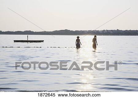Huatluco, Mexico; Two People In The Water At A Floating Dock With The Sunlight Reflecting Off The Water View Large Photo Image Stock Photography - Huatluco, Mexico; Two People In The Water At A Floating Dock With The Sunlight Reflecting Off The Water. Fotosearch