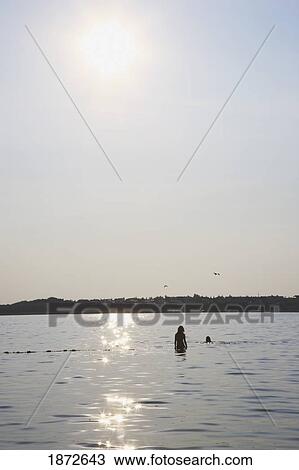 Huatluco, Mexico; Two People Wading In The Water With The Sunlight Reflecting Off The Water View Large Photo Image Stock Image - Huatluco, Mexico; Two People Wading In The Water With The Sunlight Reflecting Off The Water. Fotosearch