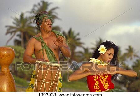 Stock Image - Hula At Sunrise On Beach With Tahitian Drummer Dancing And Playing With Pride. Fotosearch