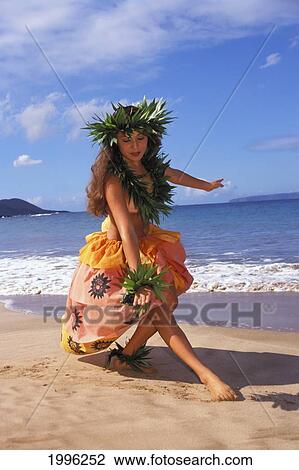 Stock Image - Hula Dancer In Colorful Outfit With Haku On Beach And Ocean Background. Fotosearch
